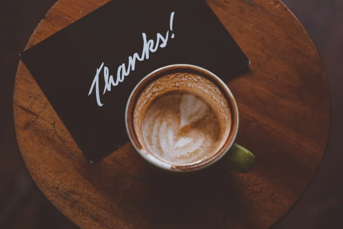 Kaffeetasse neben einer Karte mit der Aufschrift „Thanks!“